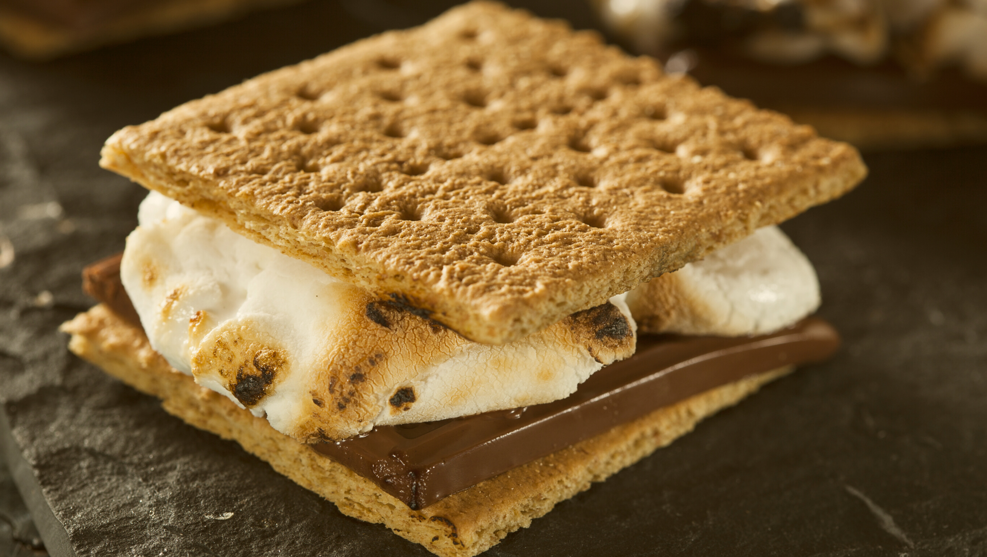 close up of a s'more with graham cracker, chocolate and marshmallows