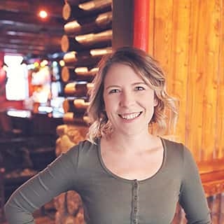 Woman in front of a log cabin wall with soft, warm lighting