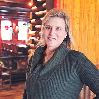 Woman in front of a log cabin wall with soft, warm lighting