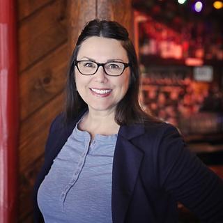 Woman in front of a log cabin wall with soft, warm lighting