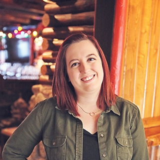 Woman in front of a log cabin wall with soft, warm lighting