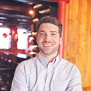 Man in front of a log cabin wall with soft, warm lighting