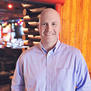 The author standing in front of a log cabin with soft, warm lighting