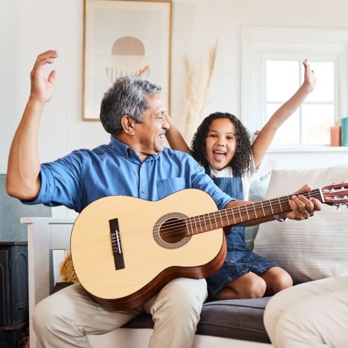 A grandfather playing guitar for his grandchild at home
