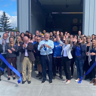 group of people cheering at business ribbon cutting