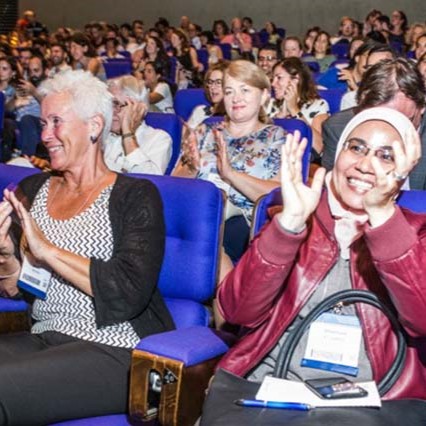 a crowd of conference attendees smiling and clapping
