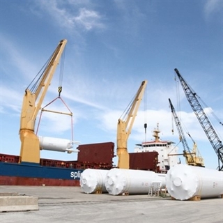 storage tanks with cranes and a ship in the background