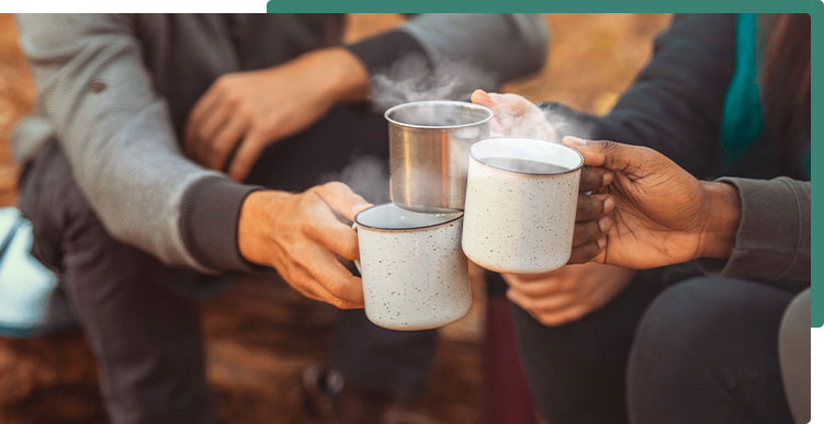 3 friends toasting with steaming camping mugs